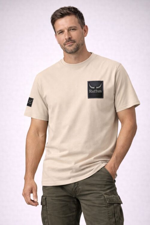 Man wearing the Ruffus Slate T-Shirt. Beige T-shirt with Ruffus Slate Design on the left chest