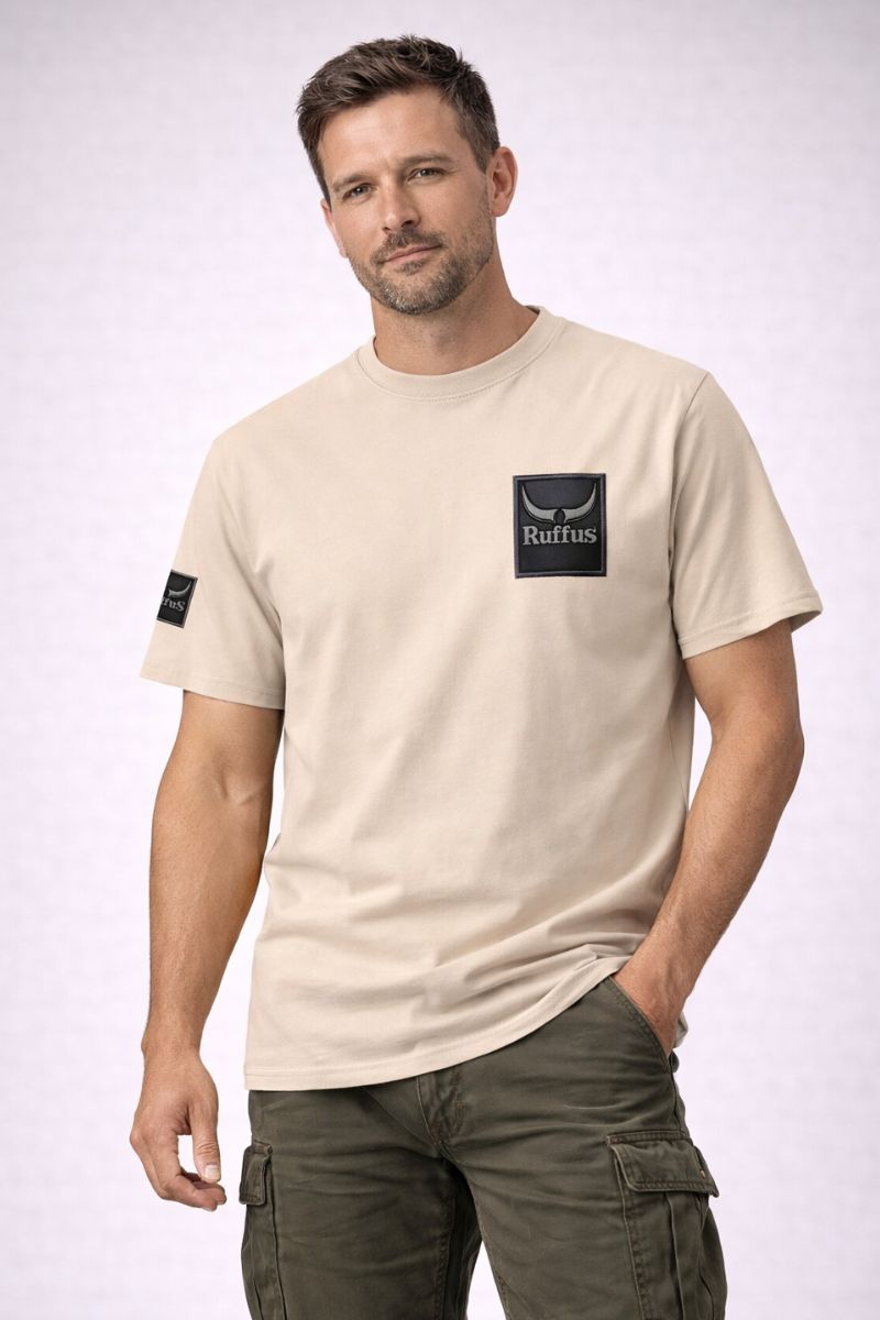 Man wearing the Ruffus Slate T-Shirt. Beige T-shirt with Ruffus Slate Design on the left chest